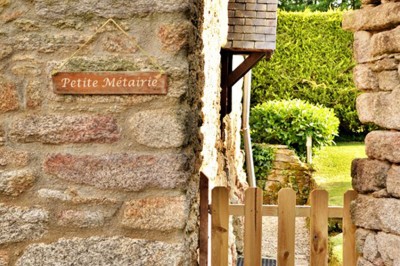 Jardin verdoyant avec pelouse, arbres dénudés, fleurs printanières et ciel bleu parsemé de nuages légers.