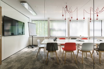 Femme assise dans un hammam aux carreaux roses, enveloppée dans une serviette blanche.