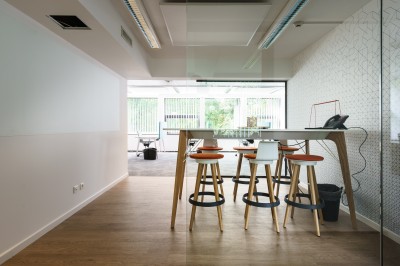 Femme assise dans un hammam aux carreaux roses, enveloppée dans une serviette blanche.