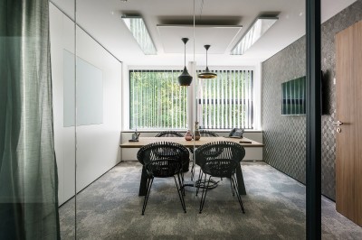 Femme assise dans un hammam aux carreaux roses, enveloppée dans une serviette blanche.