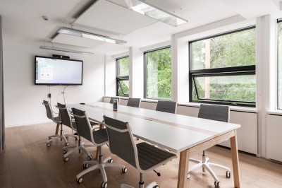 Femme assise dans un hammam aux carreaux roses, enveloppée dans une serviette blanche.