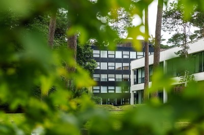 Femme assise dans un hammam aux carreaux roses, enveloppée dans une serviette blanche.