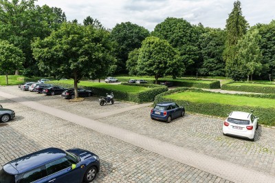 Femme assise dans un hammam aux carreaux roses, enveloppée dans une serviette blanche.