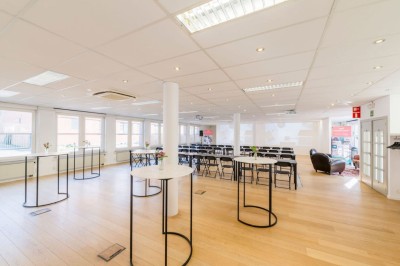 Bâtiment en briques à deux étages avec un parking adjacent et un abri en bois au premier plan.