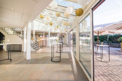 Bâtiment en briques à deux étages avec un parking adjacent et un abri en bois au premier plan.