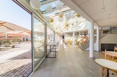 Bâtiment en briques à deux étages avec un parking adjacent et un abri en bois au premier plan.