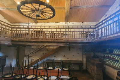 Salle vide avec sol carrelé blanc, murs décorés de bois, miroirs et portes vitrées donnant sur l'extérieur.