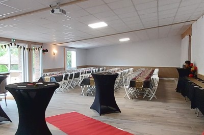 Décoration festive avec arche de ballons rouges, noirs et dorés, rideau scintillant et tapis rouge dans une salle.