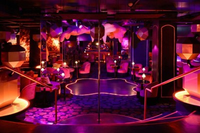 Miniature Location salle Paris 1 (Paris) - Louvre 66 #1 Décor intérieur avec fauteuils rouges, tables noires et un vase fleuri éclairé par une lumière tamisée.