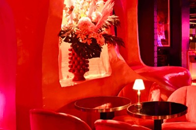 Miniature Location salle Paris 1 (Paris) - Louvre 66 #8 Décor intérieur avec fauteuils rouges, tables noires et un vase fleuri éclairé par une lumière tamisée.