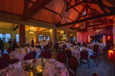 Chambre avec lit double, poutres apparentes, linge de lit blanc, et salle de bain attenante visible par une porte ouverte.