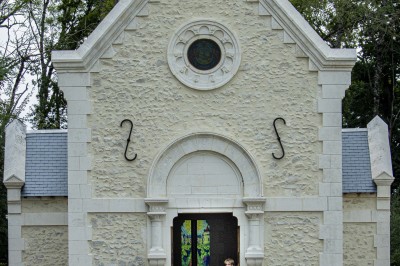 Chambre avec lit double, poutres apparentes, linge de lit blanc, et salle de bain attenante visible par une porte ouverte.