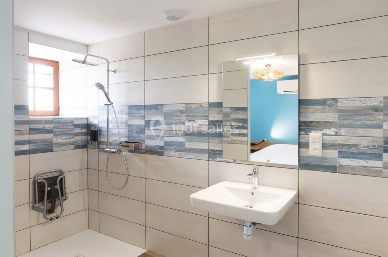 Salle de bain moderne avec douche à l'italienne, lavabo suspendu et carreaux muraux aux motifs bleus et blancs.