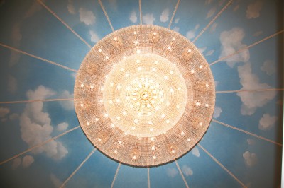 Salle de réception élégante avec tables dressées, lustres scintillants et éclairage coloré sur une scène.