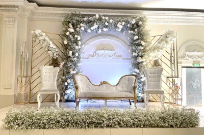 Salle de réception élégante avec tables dressées, lustres scintillants et éclairage coloré sur une scène.
