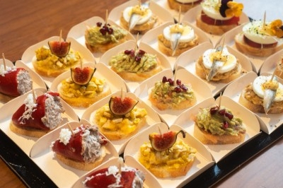 Plateau de tapas variés comprenant des toasts garnis de fruits, légumes, poissons et autres ingrédients colorés.