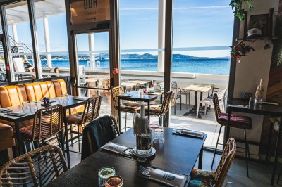Table de restaurant avec bougie fondue allumée, verres à vin et serviette pliée, ambiance chaleureuse et tamisée.