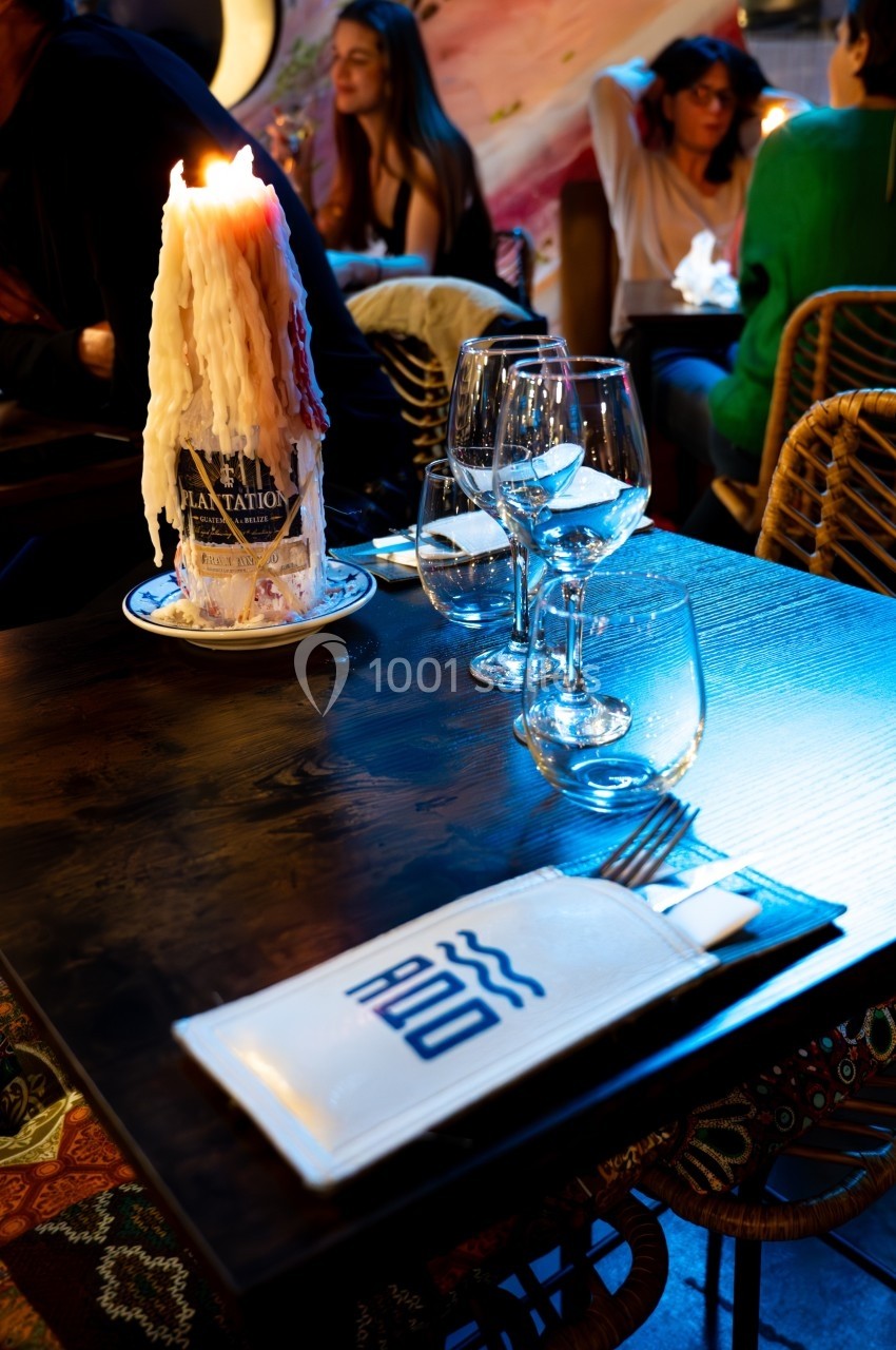 Table de restaurant avec bougie fondue allumée, verres à vin et menu posé, ambiance chaleureuse et conviviale.