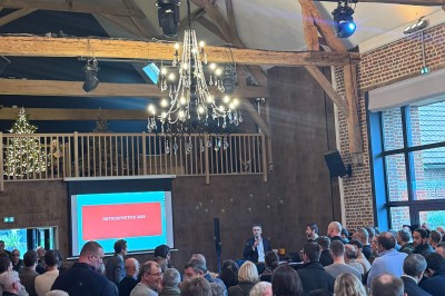 SUV vert exposé dans une salle avec parquet et murs en bois, accompagné de panneaux promotionnels en arrière-plan.