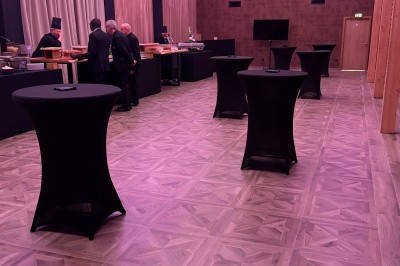 SUV vert exposé dans une salle avec parquet et murs en bois, accompagné de panneaux promotionnels en arrière-plan.