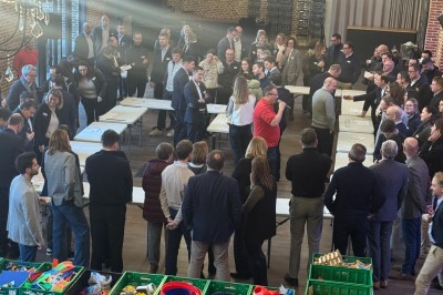 SUV vert exposé dans une salle avec parquet et murs en bois, accompagné de panneaux promotionnels en arrière-plan.