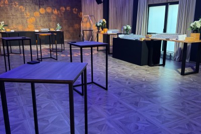 SUV vert exposé dans une salle avec parquet et murs en bois, accompagné de panneaux promotionnels en arrière-plan.