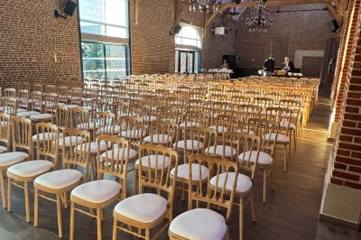 SUV vert exposé dans une salle avec parquet et murs en bois, accompagné de panneaux promotionnels en arrière-plan.