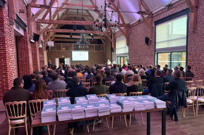 SUV vert exposé dans une salle avec parquet et murs en bois, accompagné de panneaux promotionnels en arrière-plan.