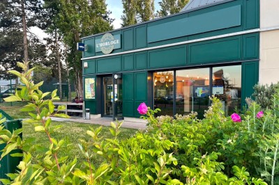 Buffet varié avec mini-burgers, samoussas, brochettes, fromages et pâtisseries, disposé sur une table près d'une baie vitrée.