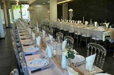 Buffet varié avec mini-burgers, samoussas, brochettes, fromages et pâtisseries, disposé sur une table près d'une baie vitrée.