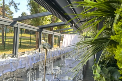 Buffet varié avec mini-burgers, samoussas, brochettes, fromages et pâtisseries, disposé sur une table près d'une baie vitrée.