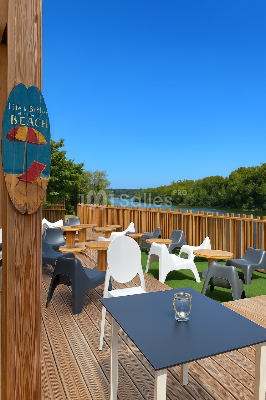 Terrasse en bois avec tables, chaises modernes et vue sur un plan d'eau entouré de végétation sous un ciel bleu.