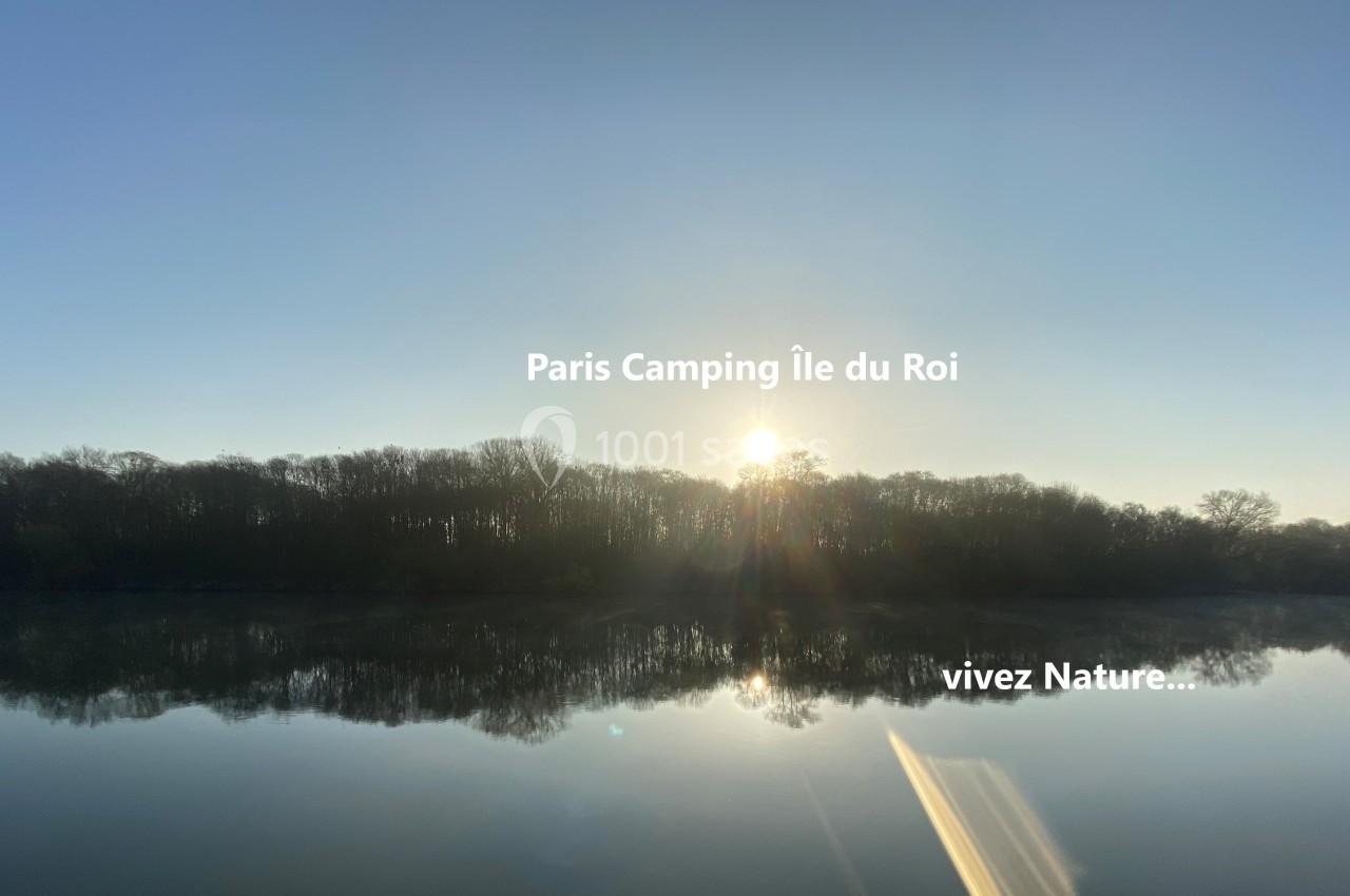 Lever de soleil sur une rivière calme entourée d'arbres, avec un texte superposé mentionnant ’Paris Camping Île du Roi’.