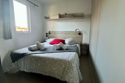 Sanitaires modernes avec cabines fermées, lavabo, murs en carrelage clair et lumière naturelle provenant d'une fenêtre et d…