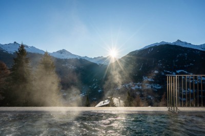 Vue aérienne d'un village de montagne enneigé entouré de sommets alpins sous un ciel dégagé.