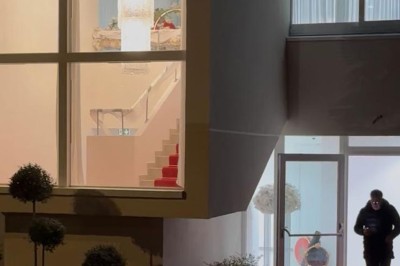 Salle de bain avec lavabo, miroir, poubelle et deux toilettes séparées par des cloisons.