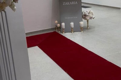Salle de bain avec lavabo, miroir, poubelle et deux toilettes séparées par des cloisons.