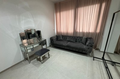 Salle de bain avec lavabo, miroir, poubelle et deux toilettes séparées par des cloisons.