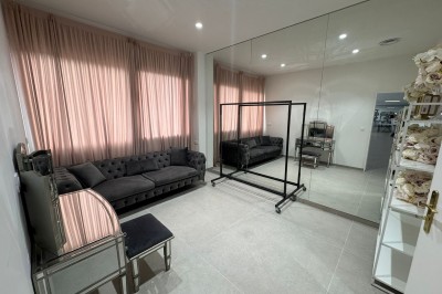 Salle de bain avec lavabo, miroir, poubelle et deux toilettes séparées par des cloisons.