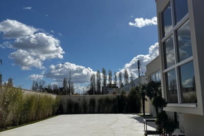Lustre en cristal suspendu dans une cage d'escalier lumineuse avec vue sur un jardin et des bâtiments à travers une grande…
