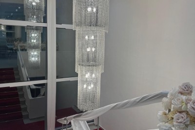 Miniature Location salle Sarcelles (Val-d'Oise) - Villa Réception #3 Salle lumineuse avec canapé gris, miroir mural, rideaux roses, étagères décorées et mobilier moderne.