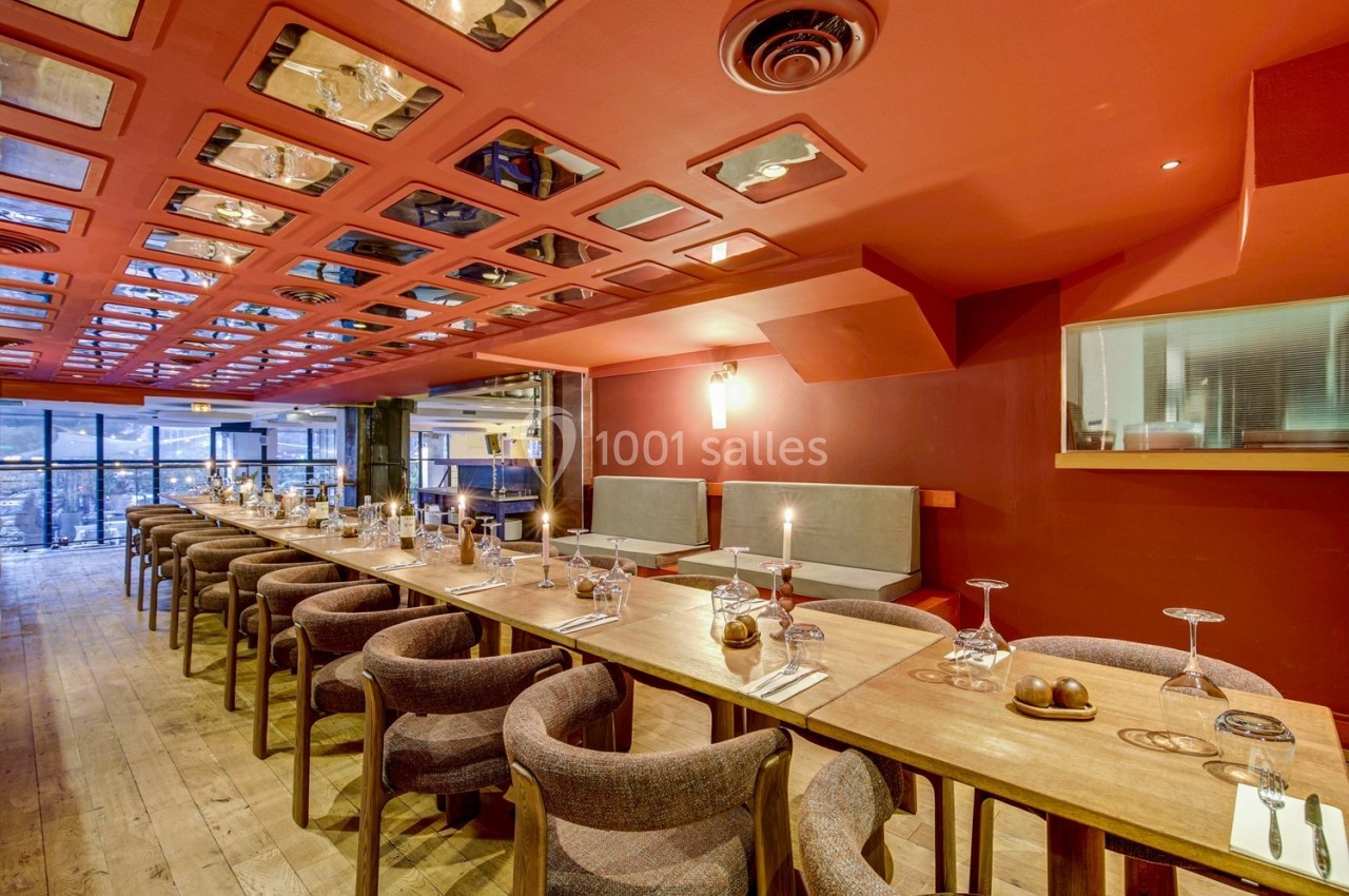 Salle de restaurant avec tables en bois alignées, chaises rembourrées, plafond décoratif et vue sur l'extérieur.