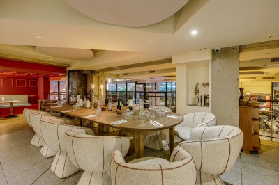 Terrasse d'un restaurant avec tables dressées, éclairage chaleureux et pergola en bois, entourée de végétation.