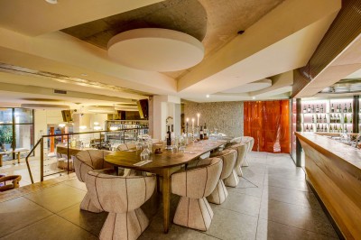 Terrasse d'un restaurant avec tables dressées, éclairage chaleureux et pergola en bois, entourée de végétation.