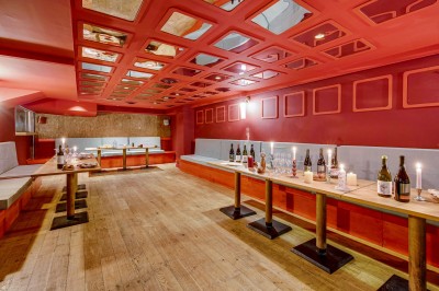 Terrasse d'un restaurant avec tables dressées, éclairage chaleureux et pergola en bois, entourée de végétation.
