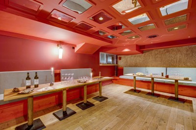 Terrasse d'un restaurant avec tables dressées, éclairage chaleureux et pergola en bois, entourée de végétation.