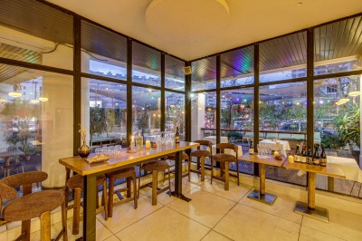 Terrasse d'un restaurant avec tables dressées, éclairage chaleureux et pergola en bois, entourée de végétation.