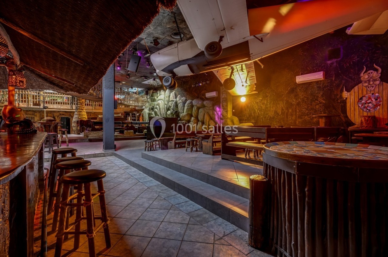 Intérieur d'un bar à thème avec décorations exotiques, éclairage tamisé et mobilier en bois.