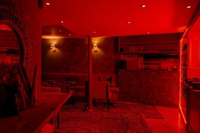 Miniature Location salle Paris 2 (Paris) - Culot #10 Salle intimiste éclairée de lumières rouges, avec canapés, petites tables rondes et rideaux sombres en arrière-plan.