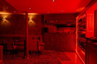Miniature Location salle Paris 2 (Paris) - Culot #15 Salle intimiste éclairée de lumières rouges, avec canapés, petites tables rondes et rideaux sombres en arrière-plan.